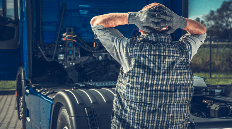 Truck driver standing frustrated beside semi-truck with open engine