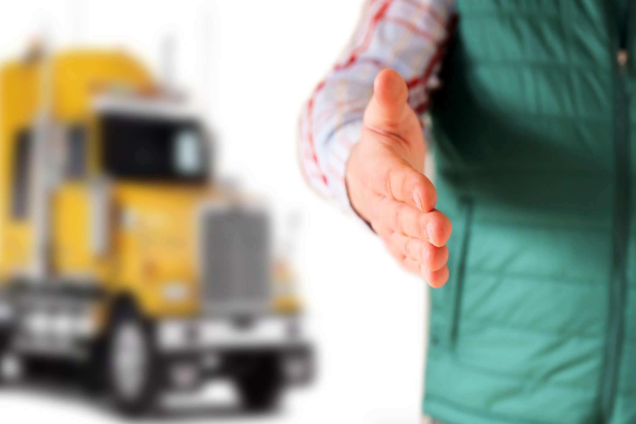 Handshake between truck driver and dispatcher with yellow semi-truck in background